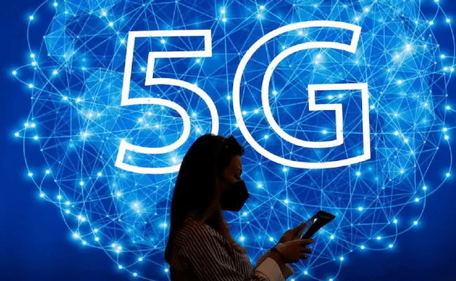 woman using phone in front of a 5g graphic illustration