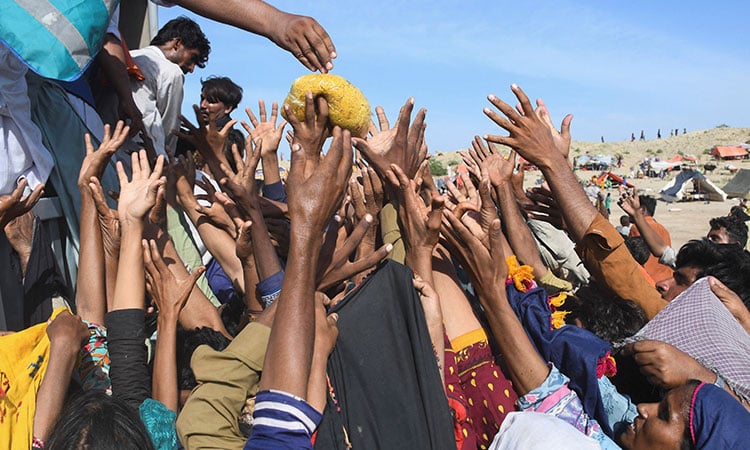 he poor people of Pakistan trying to reach for a packet of food items. (Image Source: Gulf Today