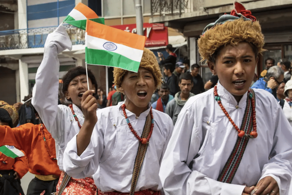 Students wearing traditional costume waveing Indian flags 