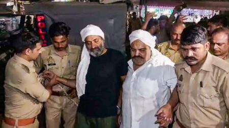 Two Men being detained by three police officers.