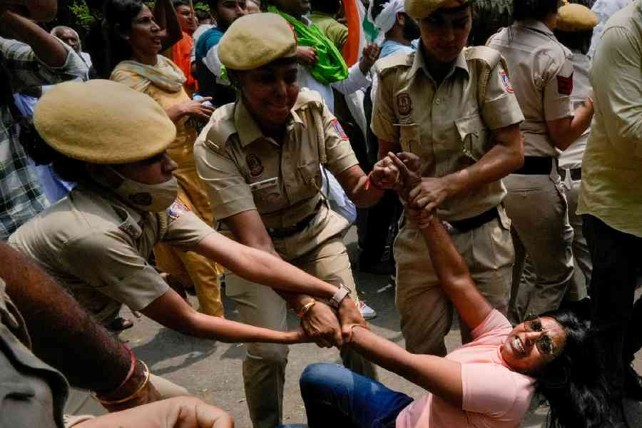 Police personnel detain an agitator during wrestlers' protest march towards the new Parliament building.