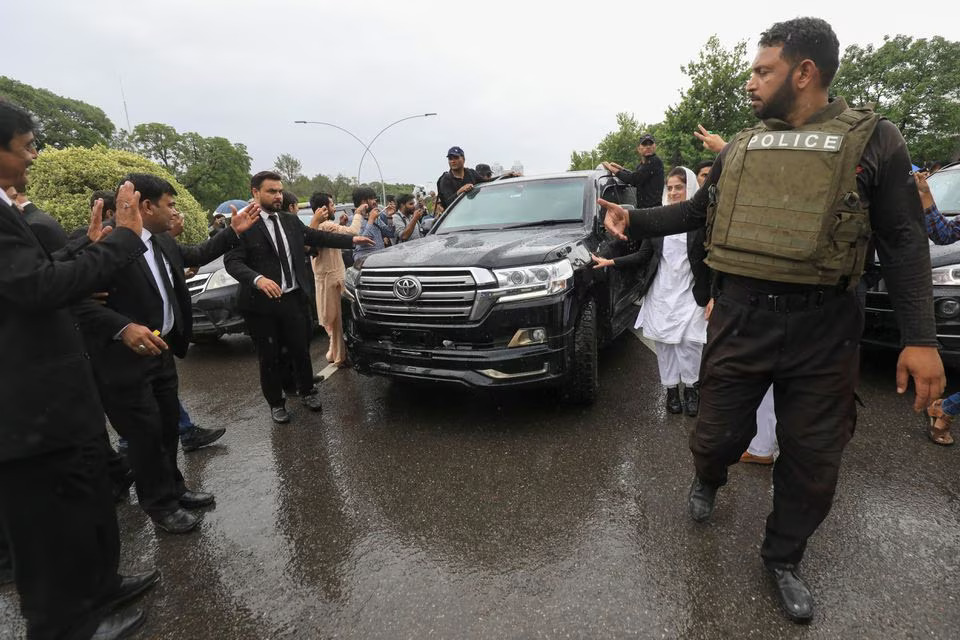 A police officer clears way for a vehicle carrying Pakistan's former PM Imran Khan as he leaves the High Court in Islamabad, Pakistan, May 31, 2024. (Image Source: Reuters)