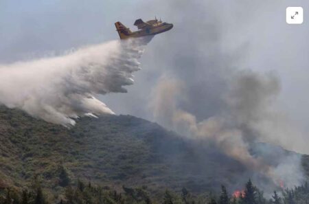 A firefighting plane drops water on the Rhodes island on 25th July