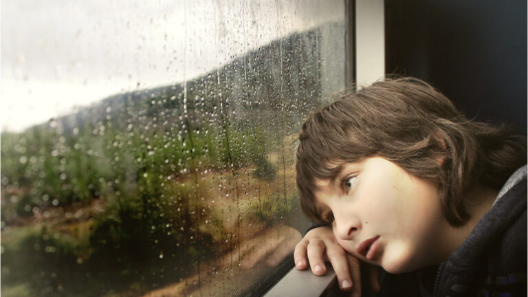 Sad young boy staring out of the window