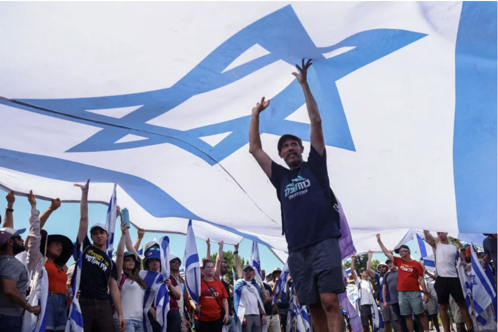 On July 24, 2024, demonstrators in Jerusalem showcased a sizable Israeli flag during a protest that occurred after a parliamentary vote on a contentious bill. The bill aimed to curtail the Supreme Court's authority to overturn certain government decisions, signalling a political crisis.