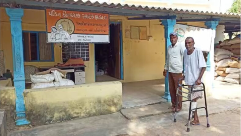 Kanti, a Dalit, (right) stands with a walker next to his ration shop, boycotted by the upper-caste Thakors