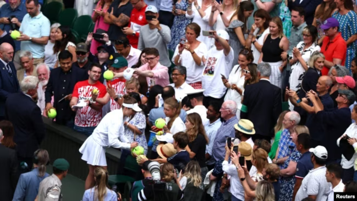 Ukraine's Elina Svitolina signs autographs after winning her quarterfinal match against Poland's Iga Swiatek at the All England Lawn Tennis and Croquet Club in Wimbledon, England, 