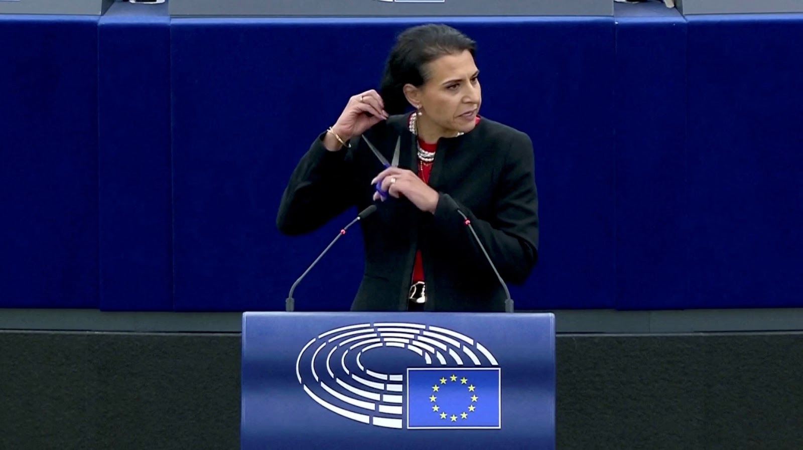 Swedish lawmaker Abir Al-Sahlani cuts her hair as she delivers a speech at EU Parliament in Strasbourg