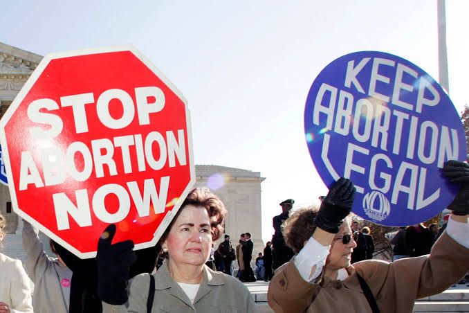 Women holding protests against the abortion law by holding placards that say " Stop Abortion Now' and "Keep Abortion Legal". 