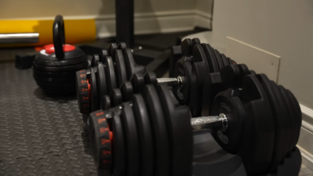 Adjustable Dumbbells on A Rack in A Home Gym Setup, Showcasing Fitness Equipment