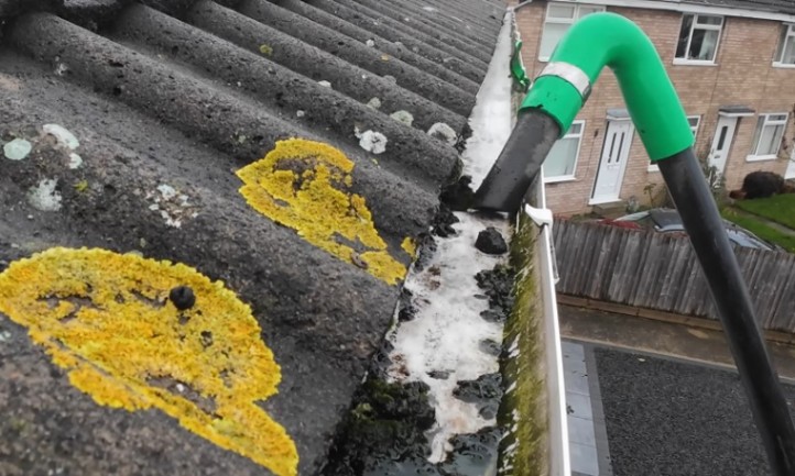 Clearing debris from residential gutters with tool