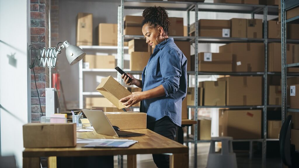 Warehouse worker labeling and inspecting packages for shipment