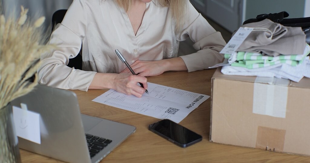 Customer filling out return form next to packaged item at desk