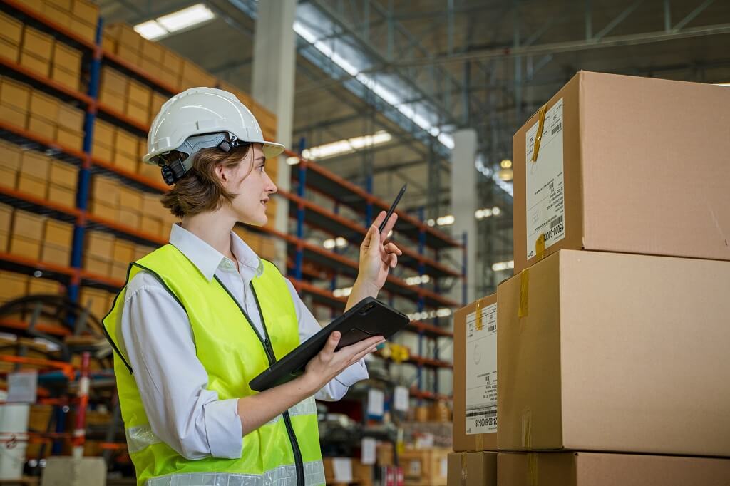 Warehouse employee scanning boxes and tracking inventory with tablet